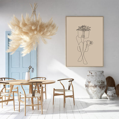 Elegant home decor: Framed wall art featuring line drawing, wooden dining table and chairs, and a large feathered decoration hanging from the ceiling in a minimalist interior.