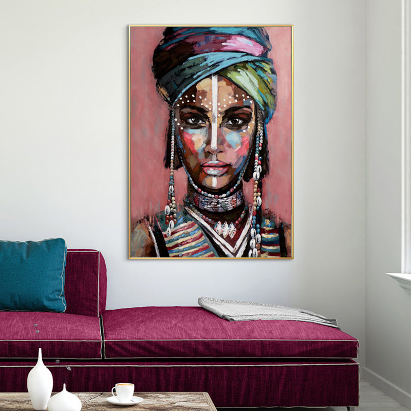 Vibrant African woman portrait - Gold Framed Print
Striking colorful painting of an African woman with intricate head wrap and jewelry, placed on a white wall above a plush pink couch.